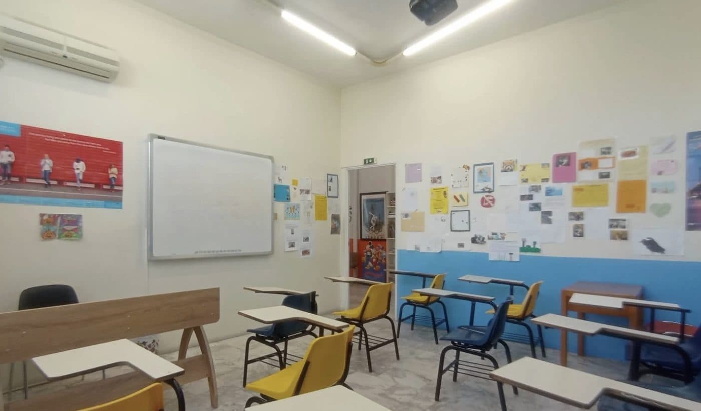 Ευρύχωρη αίθουσα με πίνακα και τοίχο γεμάτο εργασίες μαθητών, στο Κέντρο Ξένων Γλωσσών Νομικού